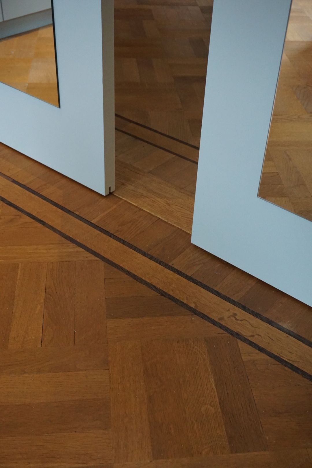 Mozaiekparket met wengé inlegband bij een deur