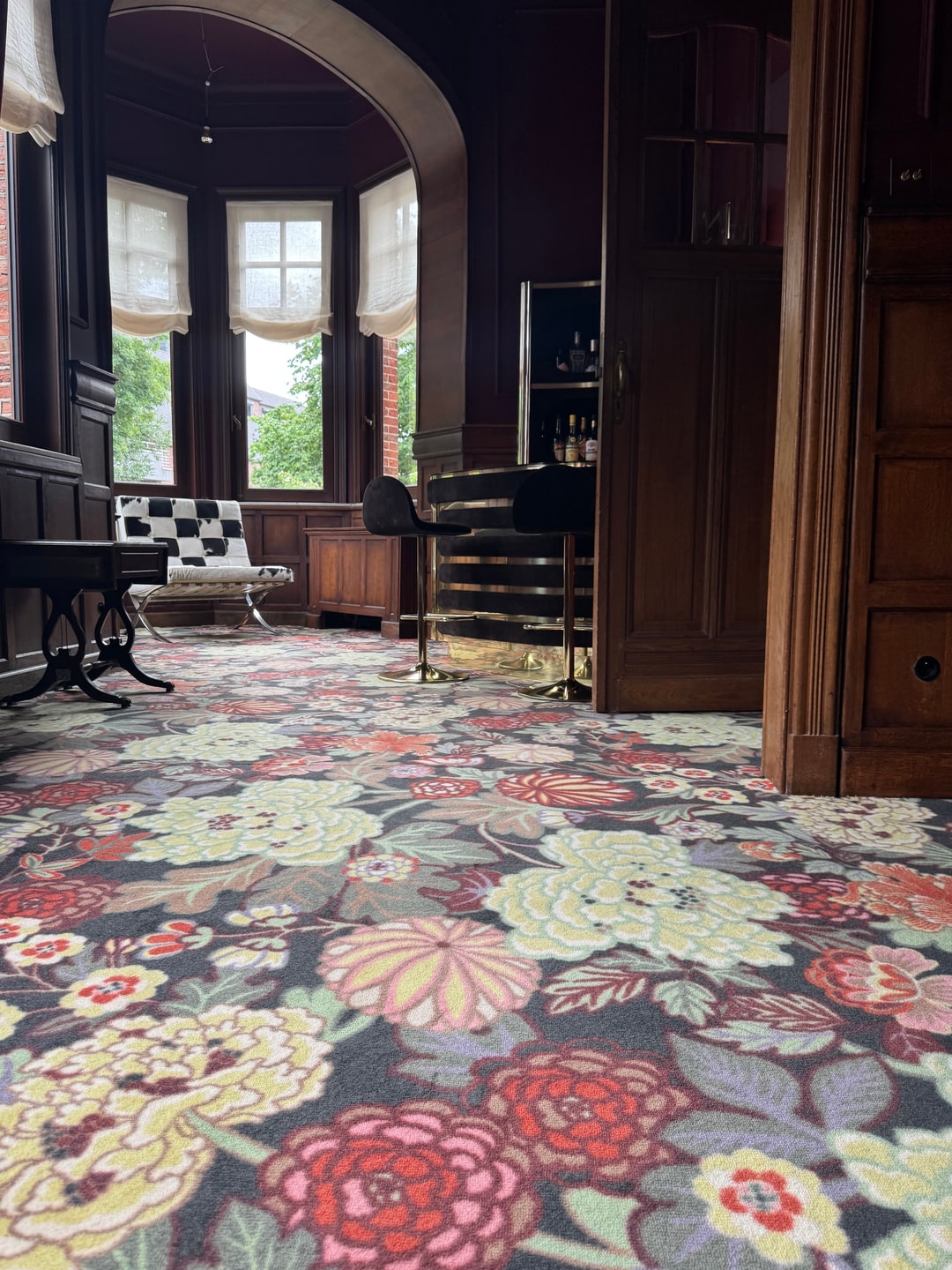 Salon met erker en houten lambrisering op een tapijt met bloemenpatroon
