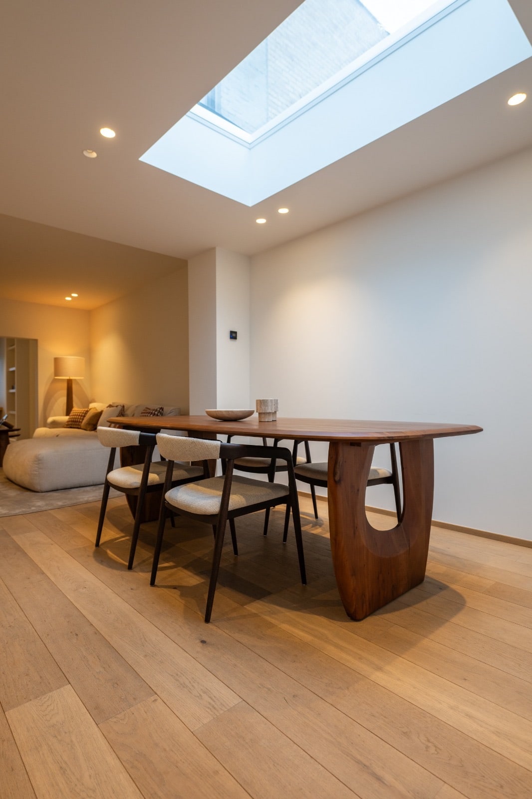 Brede plankenvloer in een leefruimte met eettafel onder een lichtkoepel
