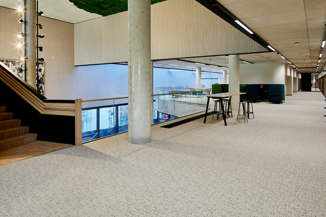 Tapijttegels in een ruim atrium met houten trap