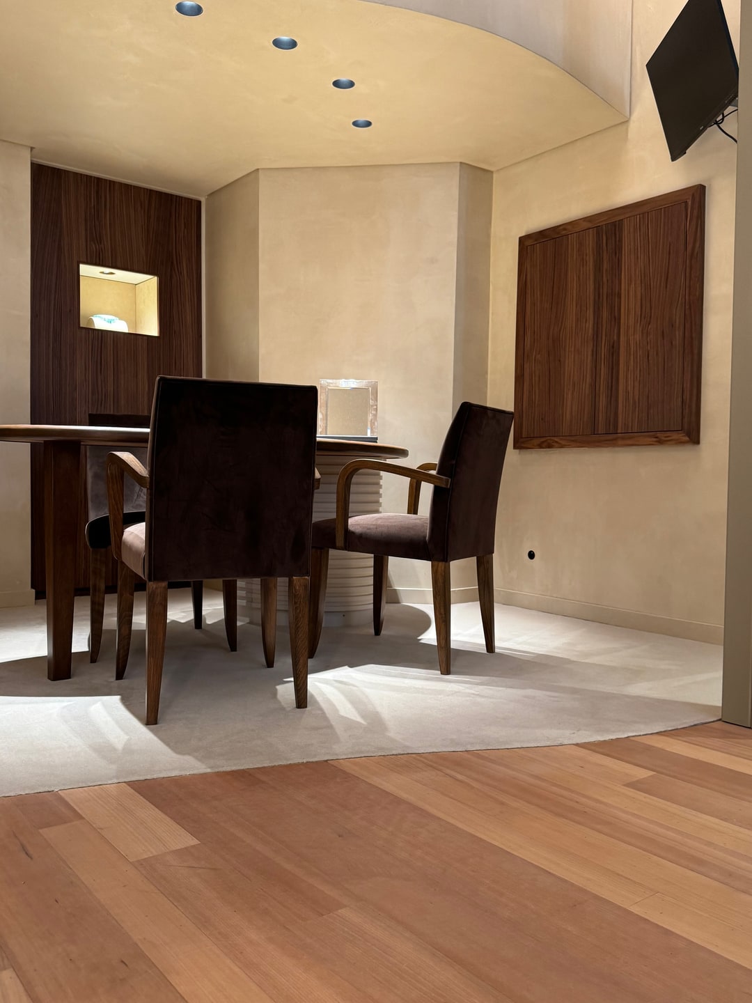Overgang van lichtbeige vasttapijt naar parket bij een eethoek met velours stoelen