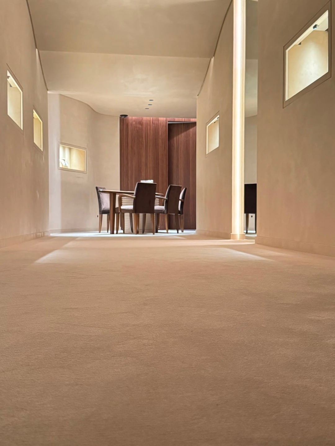 Cremekleurig vasttapijt in een warm ingerichte salon met walnoten wanden, geplaatst door Grutman Floor Concepts