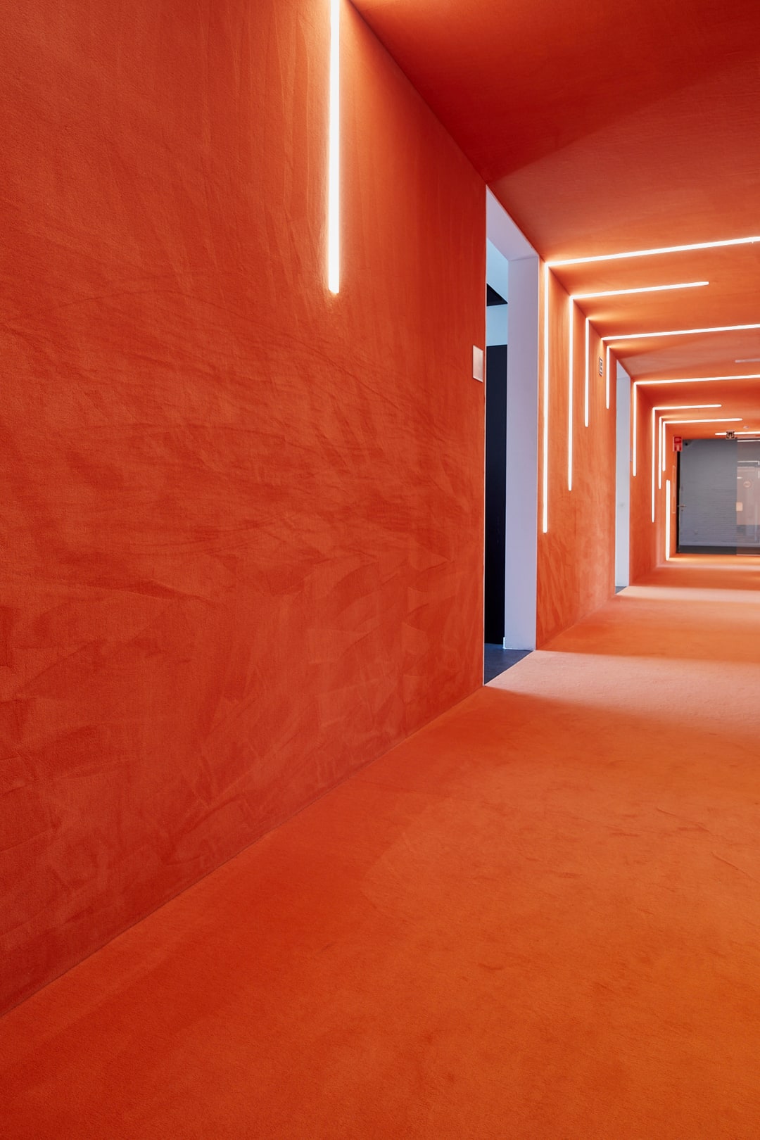 Terracotta velours vasttapijt over vloer en wanden van een gang